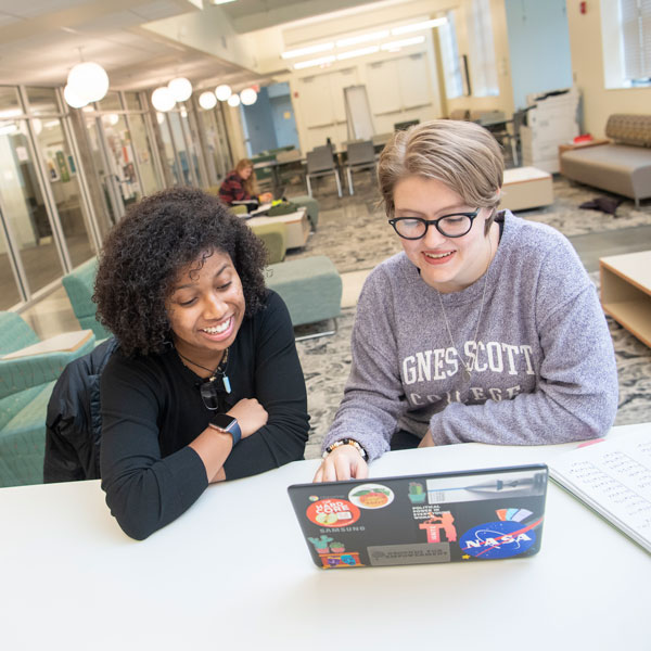 Two students sit by a laptop