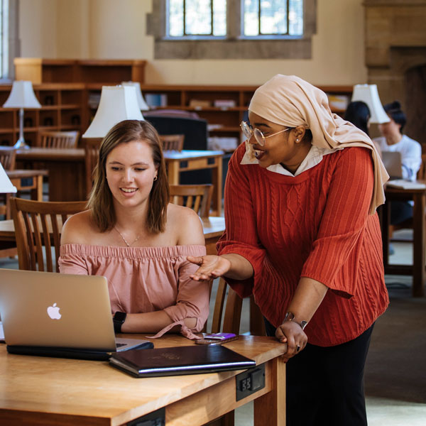 two students over computer smiling