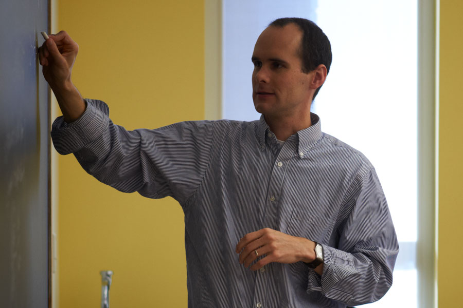 Professor writing on a board in a classroom